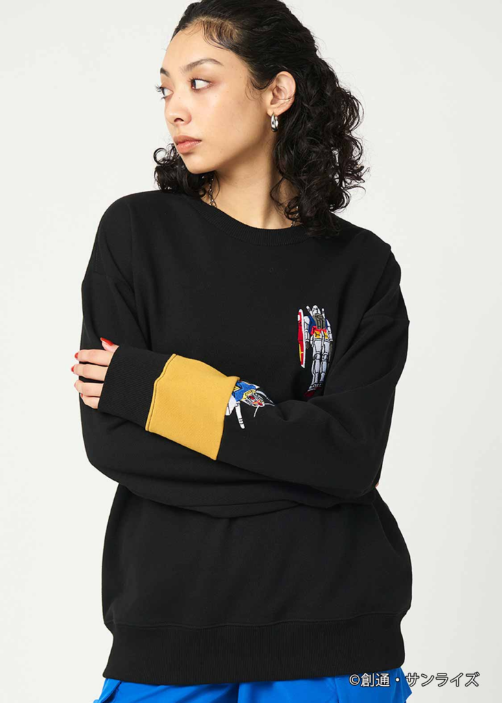 a woman with curly hair wearing a black sweatshirt with a yellow and black patch on her sleeve